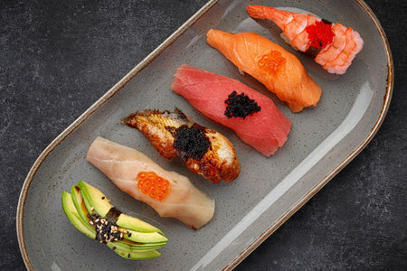 Assorted Nigiri sushi on a plate, on dark concreteの写真素材