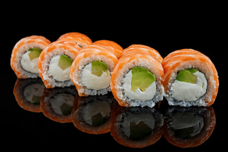 Sushi roll with salmon. avocado and cream cheese, on a black mirror with reflectionの写真素材