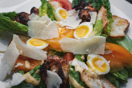 Caesar salad with eggs, chicken meat, croutons close-up on a plateの写真素材