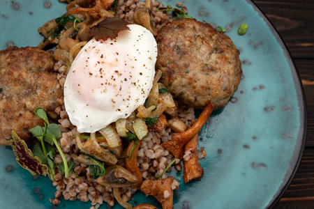 Boiled buckwheat porridge with meat cutlets, fried chanterelle mushrooms and poached eggの写真素材