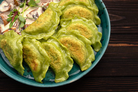 Green dumplings with spinach and fried mushrooms in creamy sauceの写真素材