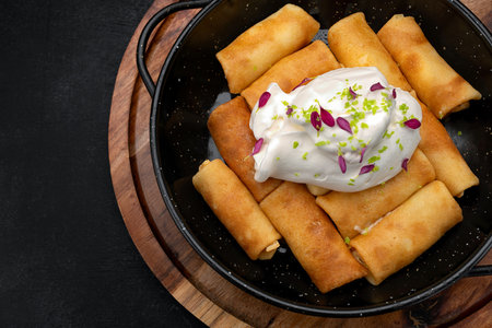 Fried pancakes with cottage cheese and sour cream in a frying pan on a wooden board