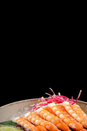 Shrimp sashimi with lime and ice on a bamboo leaf on a black backgroundの写真素材