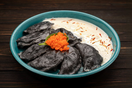 Appetizing dumplings with cuttlefish ink, salmon, shrimp, and tobiko caviar on a wooden boardの写真素材