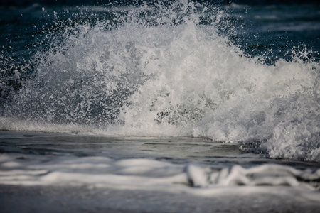 Powerful ocean wave crashes onto the shore, creating white sea foam.の写真素材