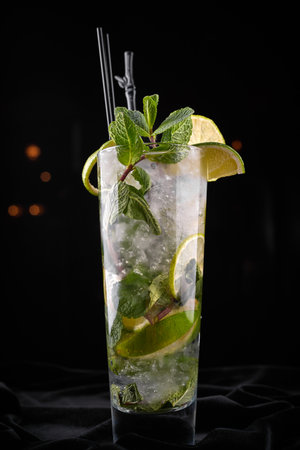 Fresh mojito cocktail with lime and mint in a clear glass, set against a black background. cool, vibrant, and refreshingの写真素材
