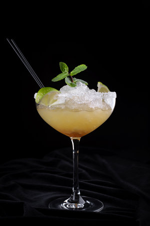 Classic margarita cocktail in a salt-rimmed glass, set against a dark backgroundの写真素材