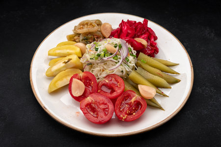 Pickled cucumbers, cabbage, tomatoes, and peppers on a plateの写真素材