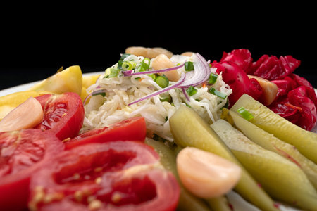 Pickled cucumbers, cabbage, tomatoes, and peppers on a plateの写真素材