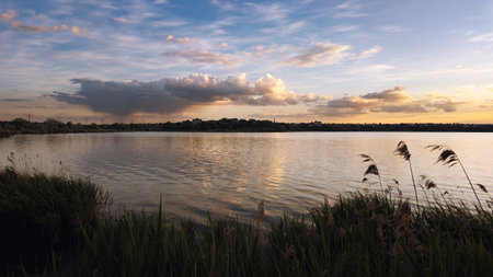 Scenic sunset view over a calm lake with soft reflections and a tranquil atmosphere. Perfect for themes of ecology, environment, and natural beauty.の写真素材