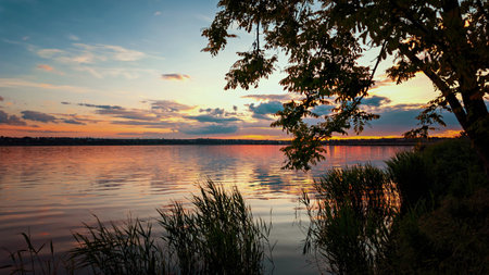 Scenic sunset view over a calm lake with soft reflections and a tranquil atmosphere. Perfect for themes of ecology, environment, and natural beauty.の写真素材