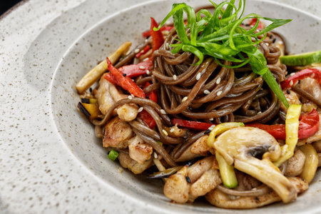 Delicious black spaghetti with mushrooms, chicken, and vegetables, perfect for restaurant menus and food advertising.の写真素材