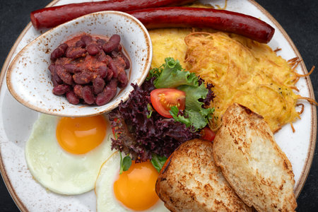 Hearty breakfast with fried sausages, eggs, toast, tomatoes, beans, and greens served on a plate.
