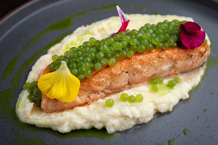 Healthy gourmet salmon fillet with vegetable puree, protein caviar and edible flowers, perfect for...