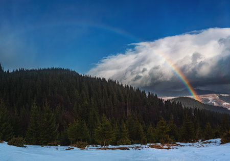 Beautiful winter rainbow over snowy mountain landscape, natural weather phenomenon and travel background.の写真素材