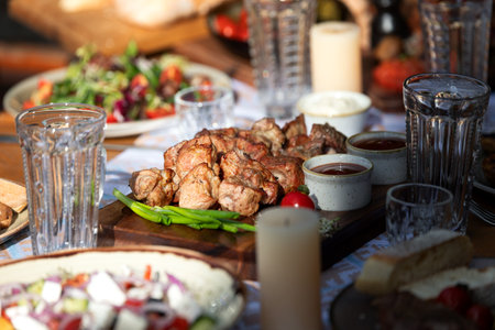 Tasty grilled barbecue kebab served on wooden board at decorated table, delicious restaurant meal concept with rustic style.の写真素材