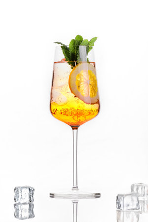 Modern transparent yellow cocktail with ice cubes on reflective mirror surface, elegant beverage concept with minimal aesthetic.の写真素材