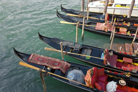 Four Venetian Gondolas, docked waiting for tourists near the Rialto Bridge on Grand canal in Venice, Italy.の写真素材