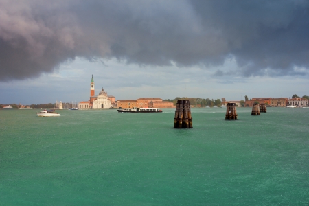 Famous landmark San Giorgio Maggiore in Venice lagoon with an overhanging clouds and summer rain pouring over the water surface.の写真素材