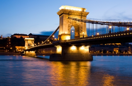 The famous landmark SzÃ©chenyi Chain Bridge on Danube river in Budapest, Hungary lit by the street lights in a peaceful summer evening. の写真素材