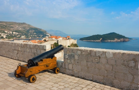 Panoramic view from the top of the citadel toward the old part of Dubrovnik in Dalmatia, Croatia with old cannon and island Lokrum at the background in a bright sunny day の写真素材