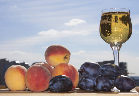 Peaches and plums with wine. Sunny day.の写真素材