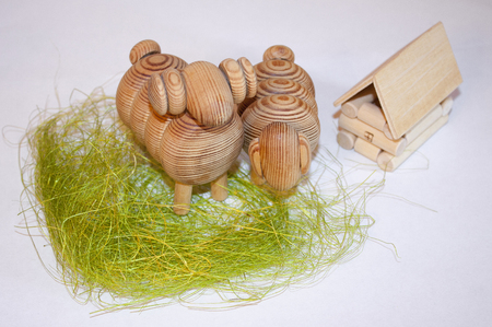 Wooden toys. A couple of sheep on the green grass near the wooden house.の写真素材