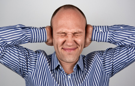 Man with eyes and ears tightly closed with handsの写真素材