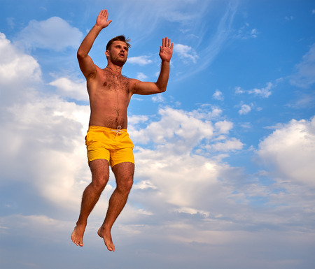 Lazurne, Ukraine - August 23, 2015: Flying man over beautiful sky at the youth festival "Crazy Days" of sport and music on the Black Sea beach. The festival gathers a lot of people. Trampoline sport.のeditorial素材