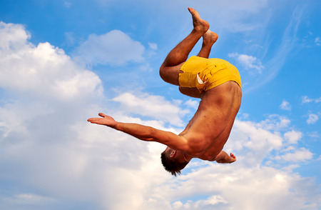 Lazurne, Ukraine - August 23, 2015: Flying man over beautiful sky at the youth festival "Crazy Days" of sport and music on the Black Sea beach. The festival gathers a lot of people. Trampoline sport.のeditorial素材