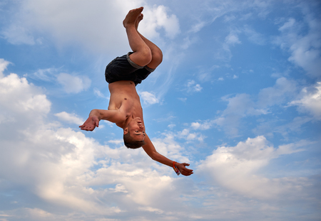 Lazurne, Ukraine - August 23, 2015: Flying man over beautiful sky at the youth festival "Crazy Days" of sport and music on the Black Sea beach. The festival gathers a lot of people. Trampoline sport.のeditorial素材