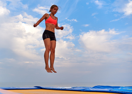 Lazurne, Ukraine - August 23, 2015: Flying girl over beautiful sky at the youth festival "Crazy Days" of sport and music on the Black Sea beach. The festival gathers a lot of people. Trampoline sport.のeditorial素材