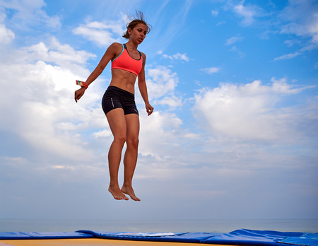Lazurne, Ukraine - August 23, 2015: Flying girl over beautiful sky at the youth festival "Crazy Days" of sport and music on the Black Sea beach. The festival gathers a lot of people. Trampoline sport.のeditorial素材
