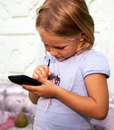 Little girl plays with smartphoneの写真素材