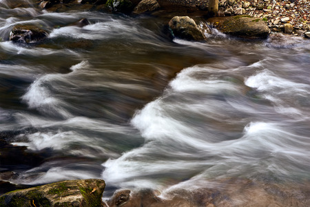 Mountain stream river with rapids under the bridgeの写真素材
