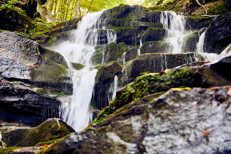 Waterfall among rocks in rocky high mountainsの写真素材