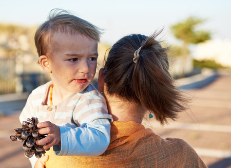 Mother plays with her little baby child outdoors in the park in sunny summer weatherの写真素材