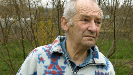 Senior elderly aged old man portrait outdoors in the vegetable kitchen garden outside the house. Country rural scene.の写真素材