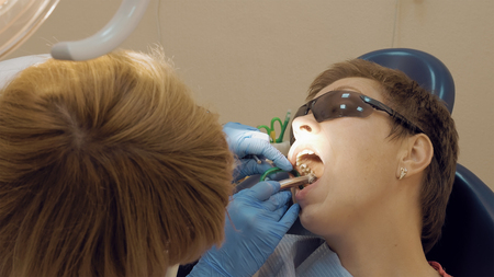 Woman at the dentist clinic office gets dental medical examination and treatment. Odontic and mouth health is important part of modern human life that dentistry help with.の写真素材