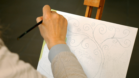 Female artist draws a pencil sketch drawing on canvas easel in art studio. Student girl learning to...