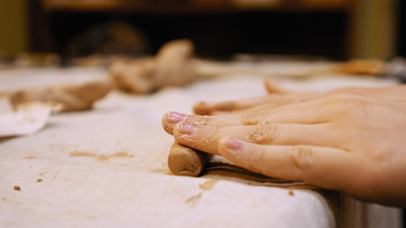 Child sculptor is pugging and kneading clay for creating pottery ceramics. Art and handicraft modelling creation.の写真素材