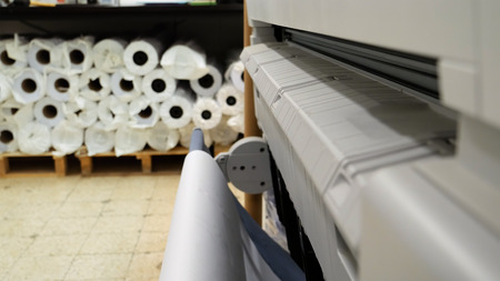 Wide format printer is printing color design draft outline sketch drawing in the printing house. Design office supply equipment.の写真素材