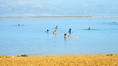 Dead Sea, Israel - May 22, 2017: Dead sea beach panoramic shot. People are bathing and swimming in the most salty sea on the planet. Dead sea is located in Middle East between Jordan and Israel.のeditorial素材