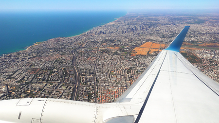 Plane is flying over the big city after takeoff. Passenger airliner is flying along the sea coast.の写真素材