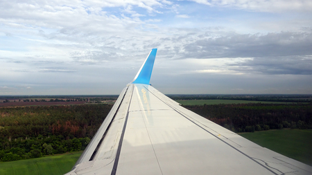 Plane is preparing for landing in European airport. Flying over green forest fields and meadows.の写真素材