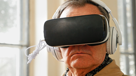 Senior old man wearing VR headset and enjoying virtual reality digital world. Virtual and augmented reality are increasingly used in human lives.の写真素材