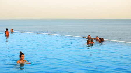 Sharm-El-Sheikh, Egypt - August 27, 2017: People are swimming in the infinity pool at the tropical sea resort at sunset. Infinity pool is an attribute of luxury resort or property estate.のeditorial素材