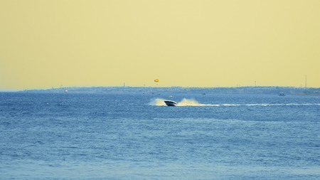 Powerboat ship at sunset is sailing along the tropical seashore. Having a good time in tropical sea or ocean.の写真素材