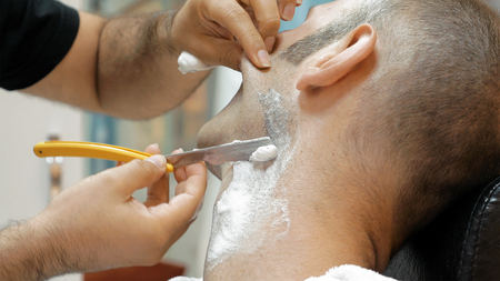 The barber is shaving his client in old fashion manner. Single blade shave gives the best result. Grooming is necessary for men and woman.の写真素材