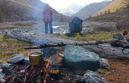 A pot on fire. A woman and a backpack. Outdoor cooking. Altai Republic, Russiaの写真素材